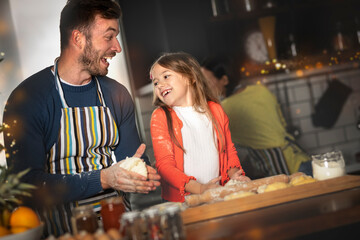 Small adorable girl preparing croissant with loving caring father on domestic kitchen.