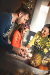 Small adorable girl preparing croissant with loving caring parents on domestic kitchen.
