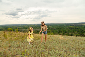 Mother and daughter as they walk through the field, having fun and laughing in summer day
