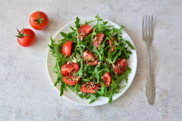 Fresh Arugula and Tomato Salad with Seeds on a White Plate with a fork