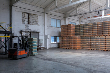 The storage and carriage at industrial food industry facility. A glass clear bottles for alcoholic or soft drinks beverages and canning jars stacked on pallets for forklift.