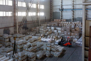 A forklift operating in a large industrial warehouse filled with stacks of aluminum ingots. A concept of logistics, raw material transportation, and heavy industry.