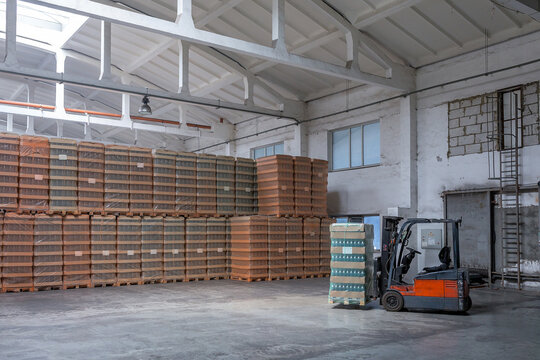 The storage and carriage at industrial food industry facility. A glass clear bottles for alcoholic or soft drinks beverages and canning jars stacked on pallets for forklift.