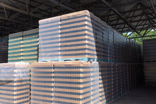 The open air storage and carriage of the finished product at industrial facility. A glass clear bottles for alcoholic or soft drinks beverages and canning jars stacked on pallets for forklift.