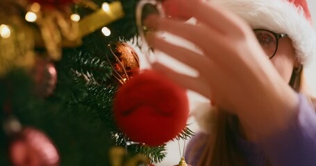 Woman Decorating Christmas Tree with Ornaments and Santa Hat - Powered by Adobe