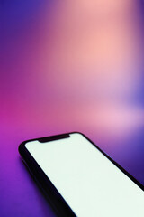 Vertical banner, close up of mobile phone with bright isolated screen on neon background. Smartphone blank mockup for showcasing mobile applications or advertisement templates. Copy space