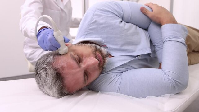 Vascular scientist using ultrasound scanning machine for examining vessels of head of adult man. Head ultrasound exam