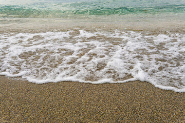 Sea foam from wave meeting clear water.