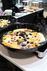 sart&eacute;n honda con revuelto de huevos, jam&oacute;n y aceitunas negras fri&eacute;ndose en el fog&oacute;n de la cocina