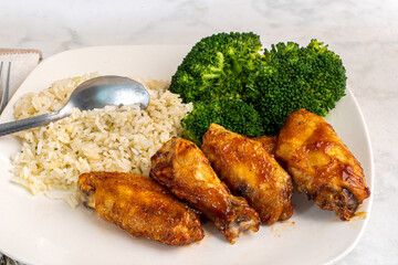 chicken wimgs  and drumsticks with rice and broccoli