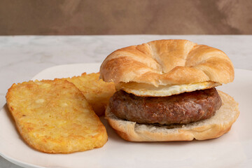 croissant breakfast sandwich with  hash browns,