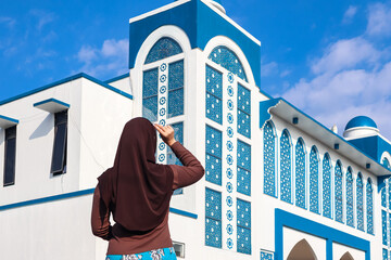 Young Asian Muslim woman wearing hijab posing in front of Mosque.