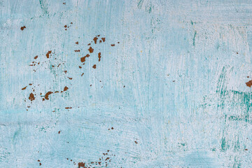 Grungy outdoor wall displays weathered light teal paint and patches of rust. Aged texture conveys...