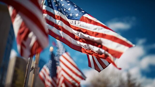 American flags wave in the wind, red and white stripes and blue stars against a sunny sky