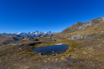 High mountain panorama in late summer, early autumn, with green and yellow larches, blue sky, in the Swiss Alps.