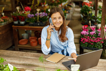A young woman works at a charming garden shop, showcasing vibrant flowers and using modern tools to boost productivity