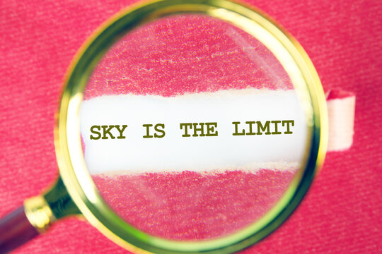 A close-up view through a magnifying glass reveals the motivational phrase sky is the limit on torn paper. This vibrant background sparks imagination and possibilities