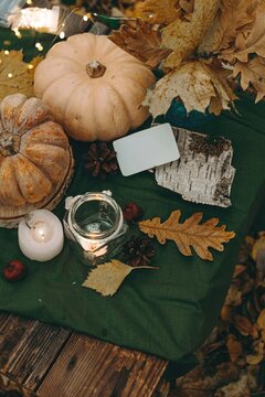 Atmospheric cozy autumn composition. Pumpkins, fall leaves, chestnut, candels. Thanksgiving day. Elegant rustic decor. Concept of cozy fall home atmosphere, aromatherapy. Copyspace.