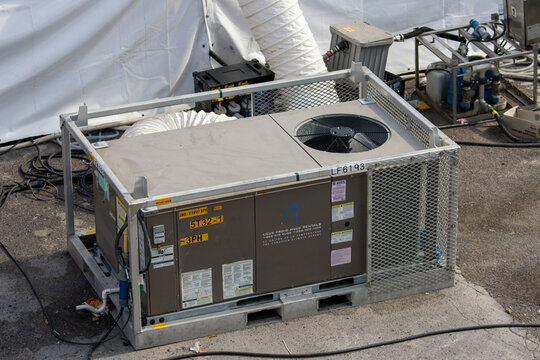 Quebec, Canada, 05 July 2025 : Outdoor industrial HVAC unit surrounded by wires, connectors, and protective fencing