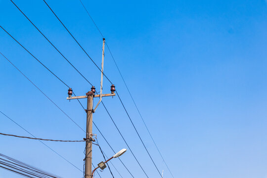 Electric pole and power cables with a clear blue sky in the background.