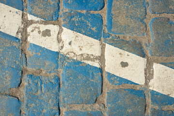 White diagonal line on old granite cube painted blue. Texture, paint, surface, rough. Design space. Top view.