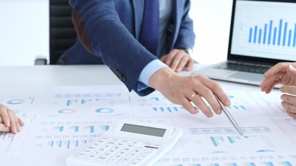 Business people's hands reviewing company performance and investment planning using graphs, pie charts, and a calculator on a desk during a collaborative workflow session