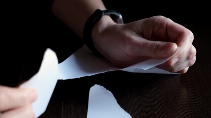 Female hands tearing paper sheet on black background. Concept of problems, frustration, dismissal, destruction, tension in professional or personal settings. Stress relief. High quality 4k footage. - Powered by Adobe