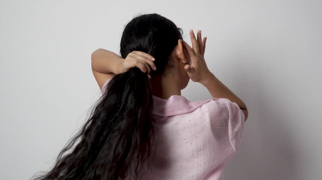 Little girl is gathering her long hair to tie it up
