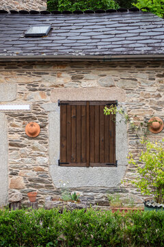 Facade of a rustic stone house with traditional wooden window shutters.