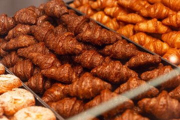 Lots of croissants on display in a store. Traditional, delicious, fresh baked goods. Close-up.