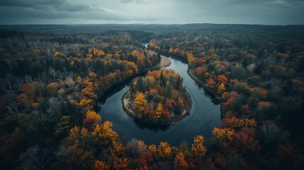 A gentle, meandering river gracefully curves through a forest with diverse autumn tones
