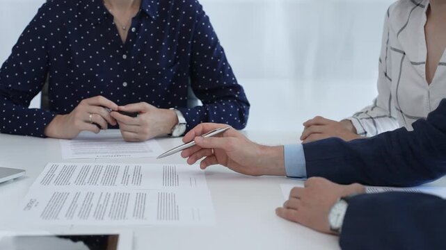 Corporate professionals analyzing contract details, gesturing toward key points while negotiating partnership terms in modern office boardroom