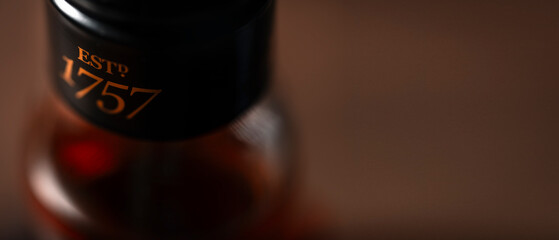 Macro shot of a whiskey bottle neck with elegant typography “ESTD 1757” in warm lighting. Artistic focus on vintage design