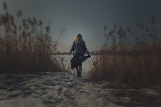 Lone fantasy figure of a mysterious woman in a dark, flowing robe standing on a vast desert dune under a dramatic, stormy night sky. - Powered by Adobe