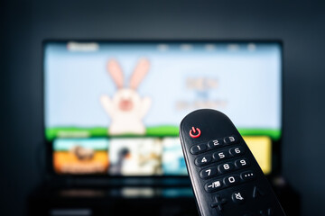 TV for kids. Child watching television. Movie for children. Cartoon video on screen and remote. Screentime for toddler or baby. Home living room at night. Change channel. Film stream.