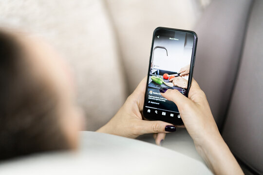 Video on social media. Short reel content in phone. Teen watching viral trend. Woman scrolling clips on mockup platform app in smartphone in hand. - Powered by Adobe