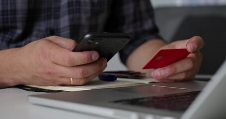 Man using smartphone and red credit card for mobile payment. Concept of fintech, convenience, and digital transaction via phone. - Powered by Adobe