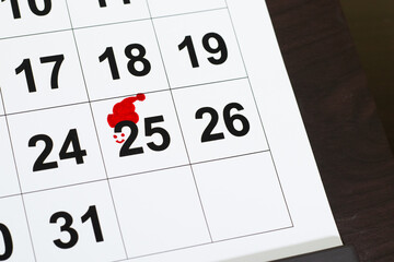 Hand drawin christmas santa red hat on the calendar marked 25 to celebrate christmas and holiday season.