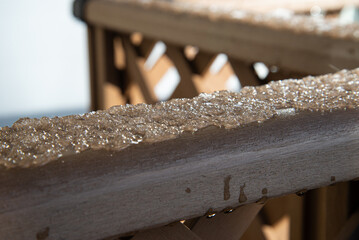 木製の手すりに溶け始めた氷と水滴のクローズアップ