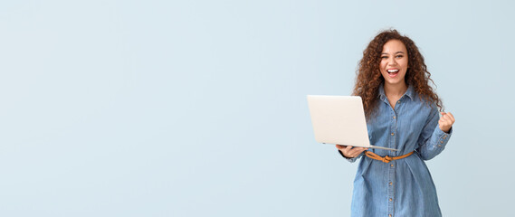 Happy African-American woman with laptop on color background