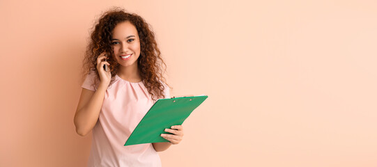 Young African-American businesswoman with documents talking by phone on color background