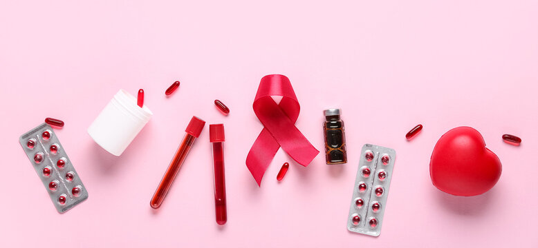Red ribbon with pills, test tubes and heart on pink background. Blood Cancer Awareness Month