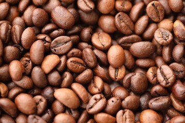 Big pile of fresh roasted brown coffee beans as flat background photo image with visible details close up