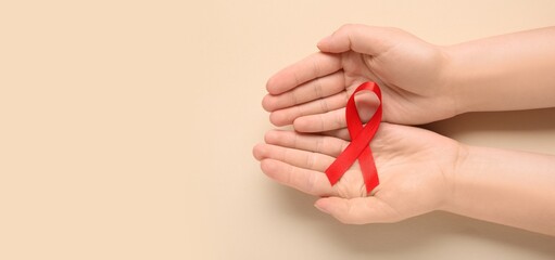 Hands with red ribbon on beige background with space for text
