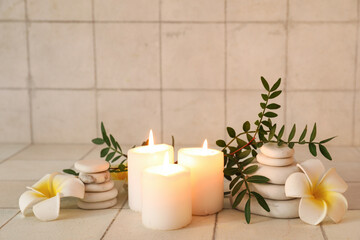 Spa composition with flowers, candles and spa stones on tile background