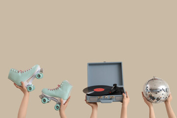 Female hands with vintage vinyl record player, disco ball and roller skates on beige background