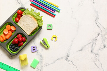 Lunch box with tasty food and school stationery on white background, top view