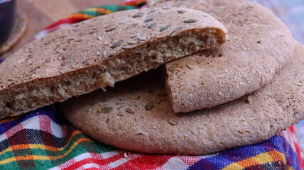 Traditional Moroccan seeded khobz . homemade round bread on colorful cloth, close-up showing crumb and texture