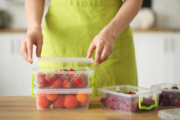 Young woman closing container with berries for freezing at home