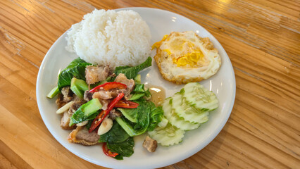 Thai Stir-fried Baby Cabbage with Pork Belly served with rice and fried egg on white plate